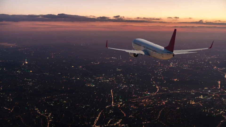 plane flying in sky at sunset