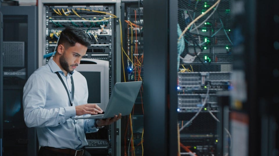 Engineer using laptop in the server room