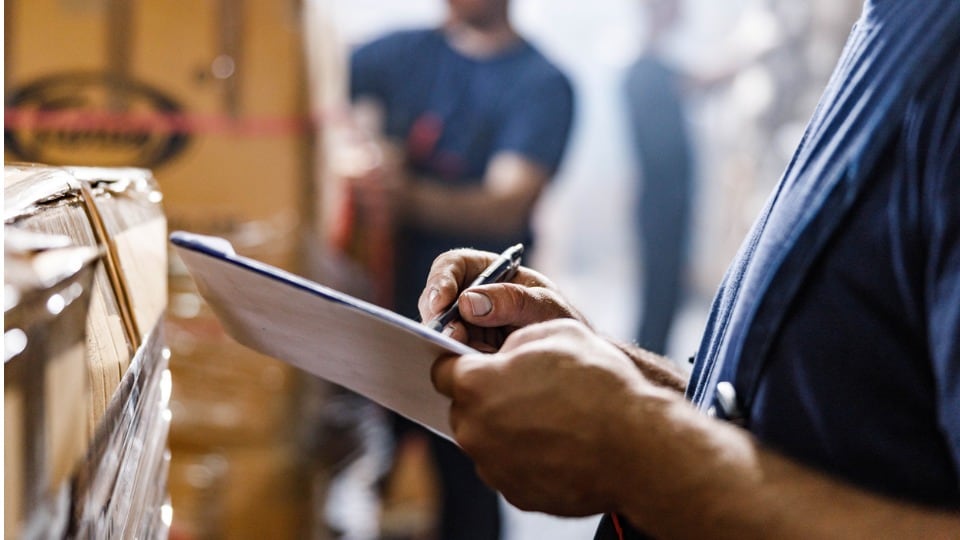 Close up of worker reviewing a checklist before freight delivery