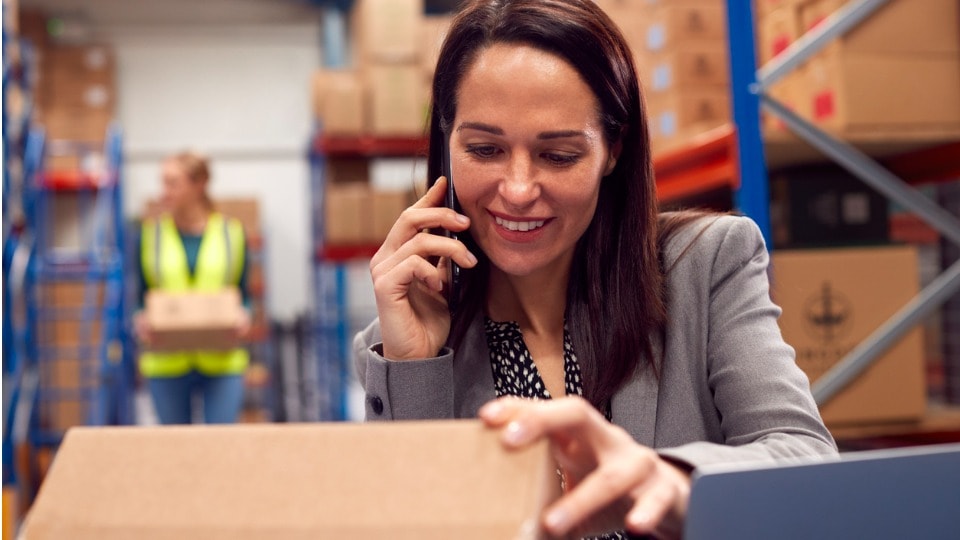 Team leader talking on a mobile device while inspecting a package