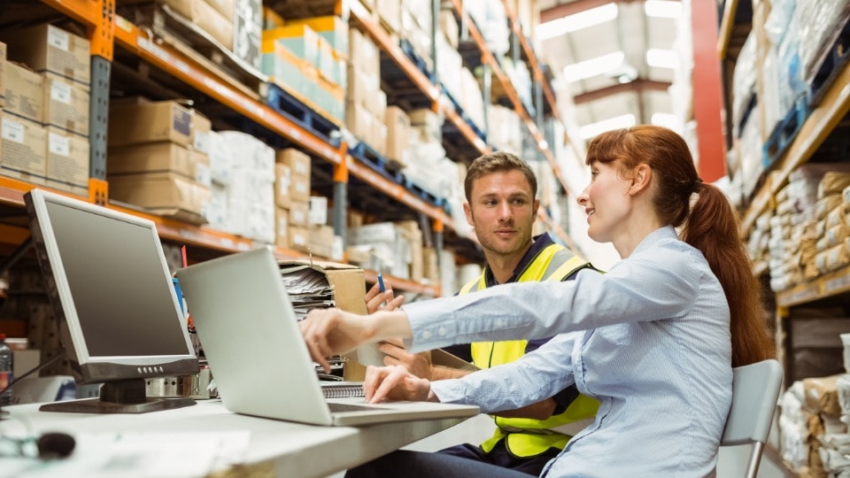 Warehouse worker and manager looking at laptop in the warehouse