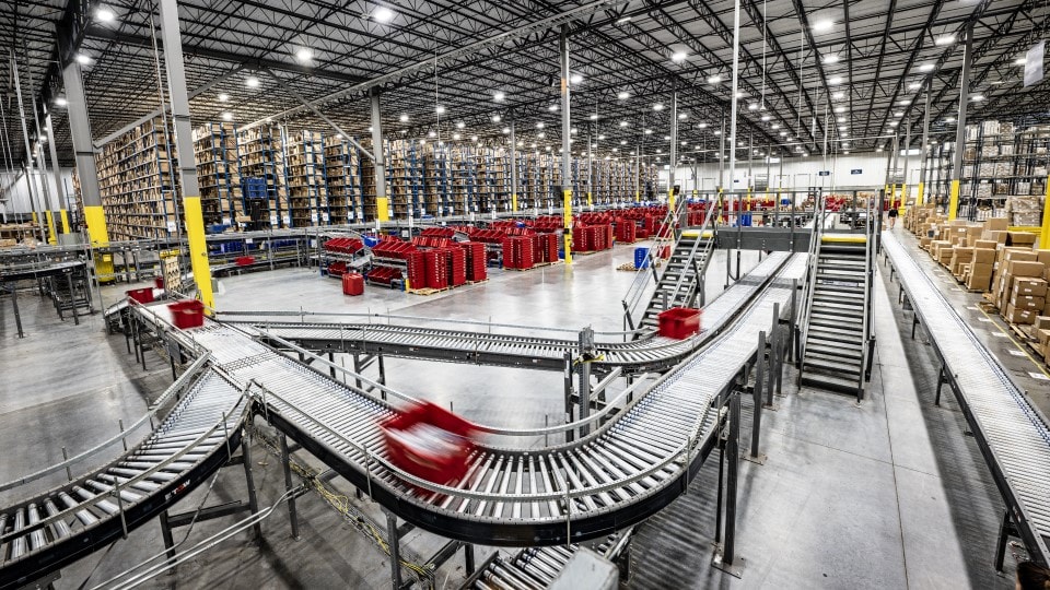 red container rolling across a conveyor belt in warehouse