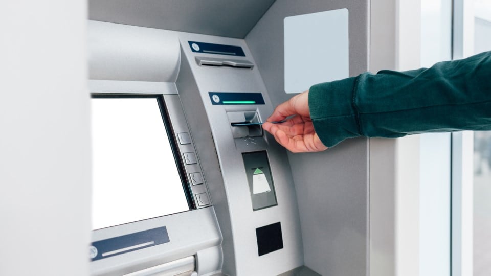 Person putting a bank card inside of automated teller machine