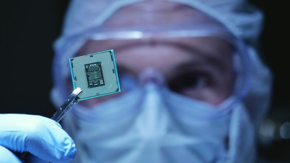 manufacturing engineer holding a microchip in a sterile environment