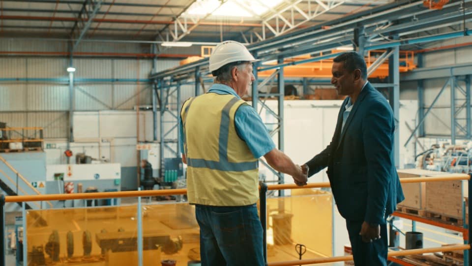 Two men shaking hands in a warehouse 