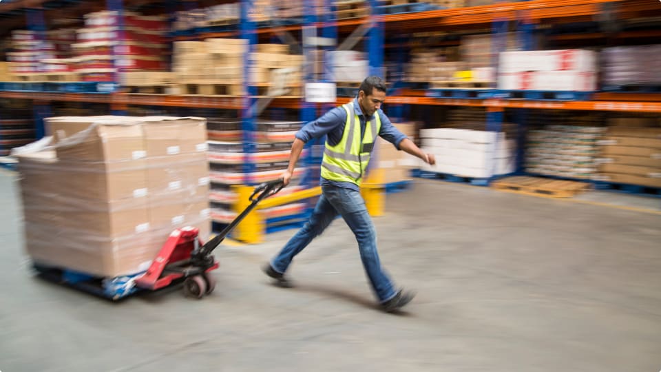 Warehouse worker pulling shrink-wrapped pallet